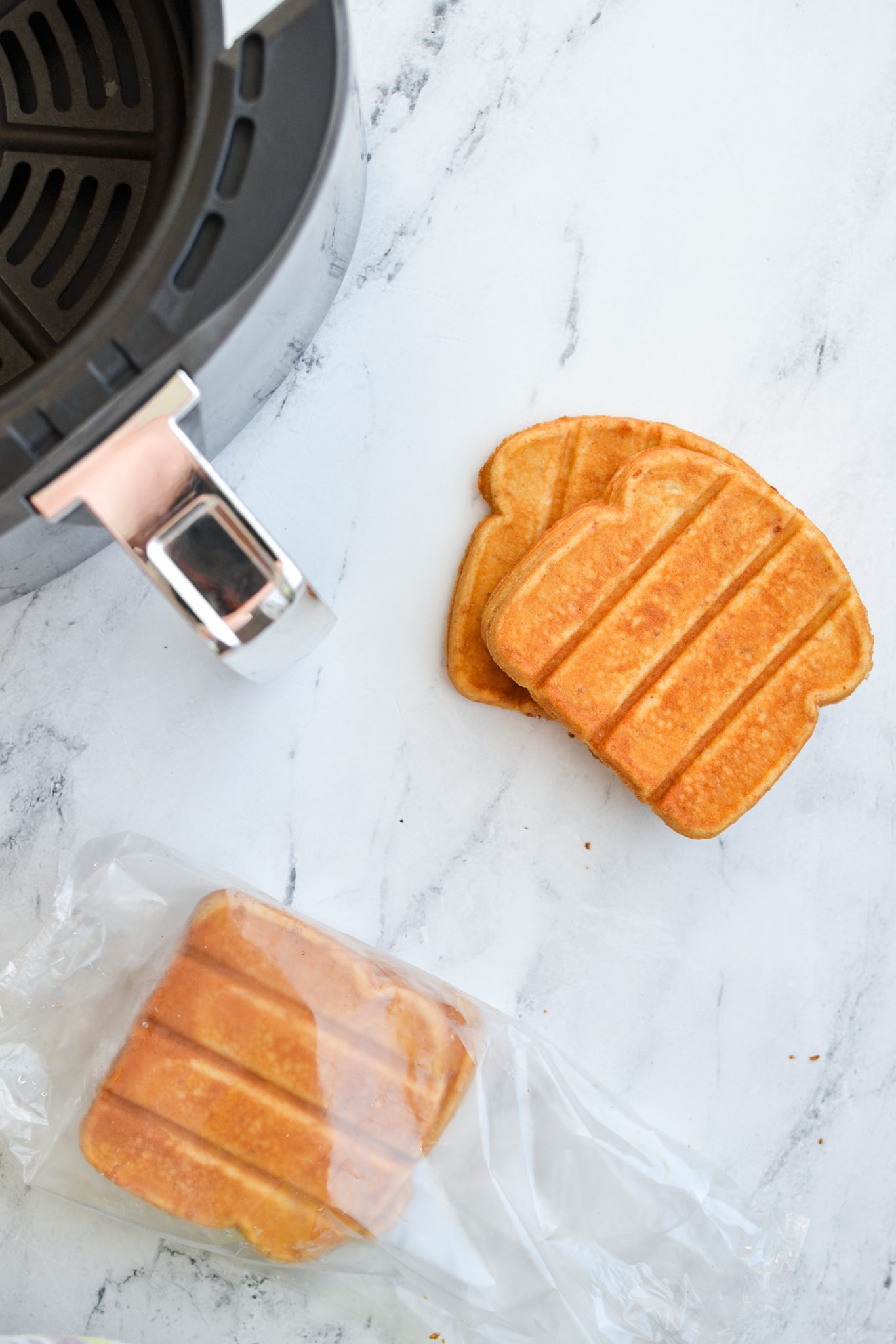 Frozen French toast sticks with an air fryer basket in the background.