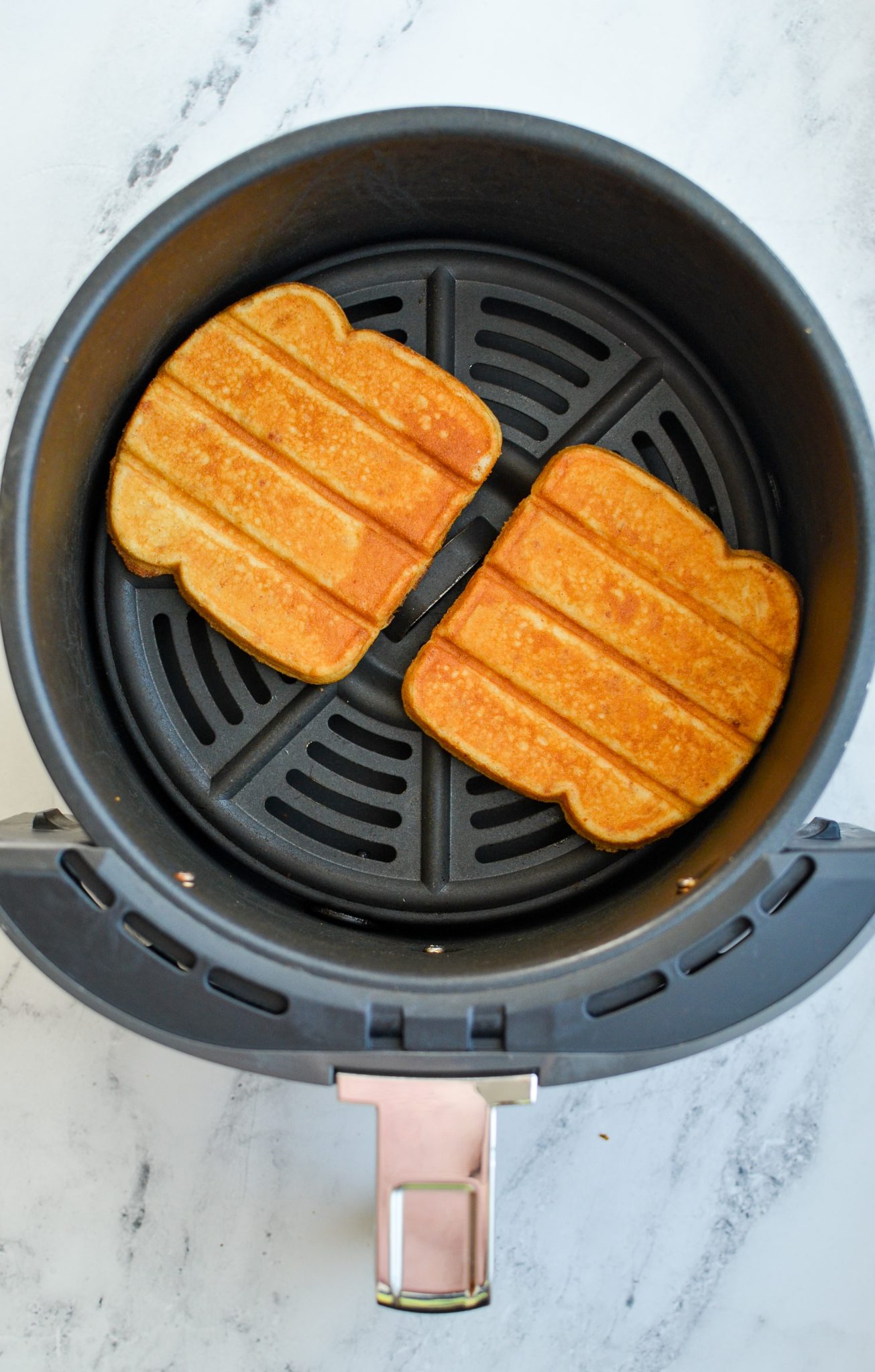 Browned French toast sticks in an air fryer basket.