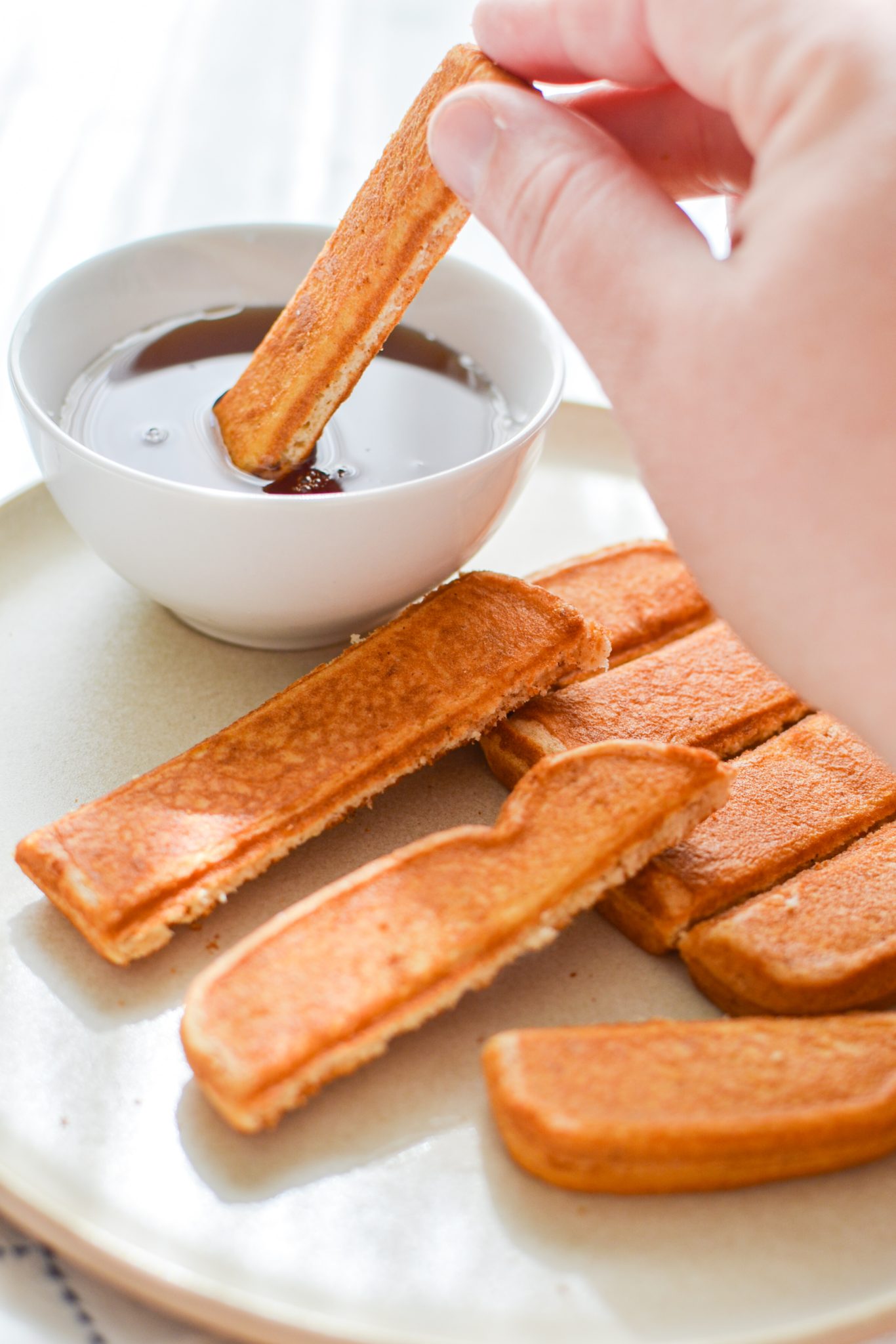 Dipping a French toast stick into maple syrup.
