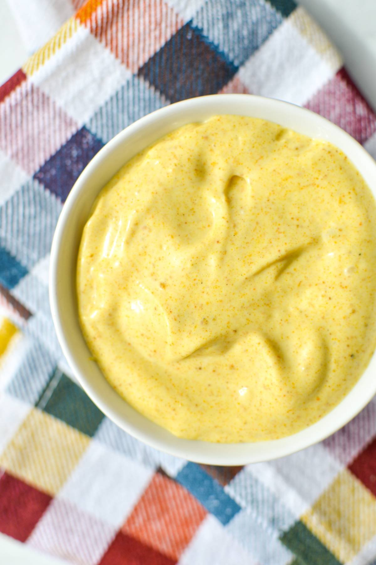 A small bowl of curry aioli on a check napkin.