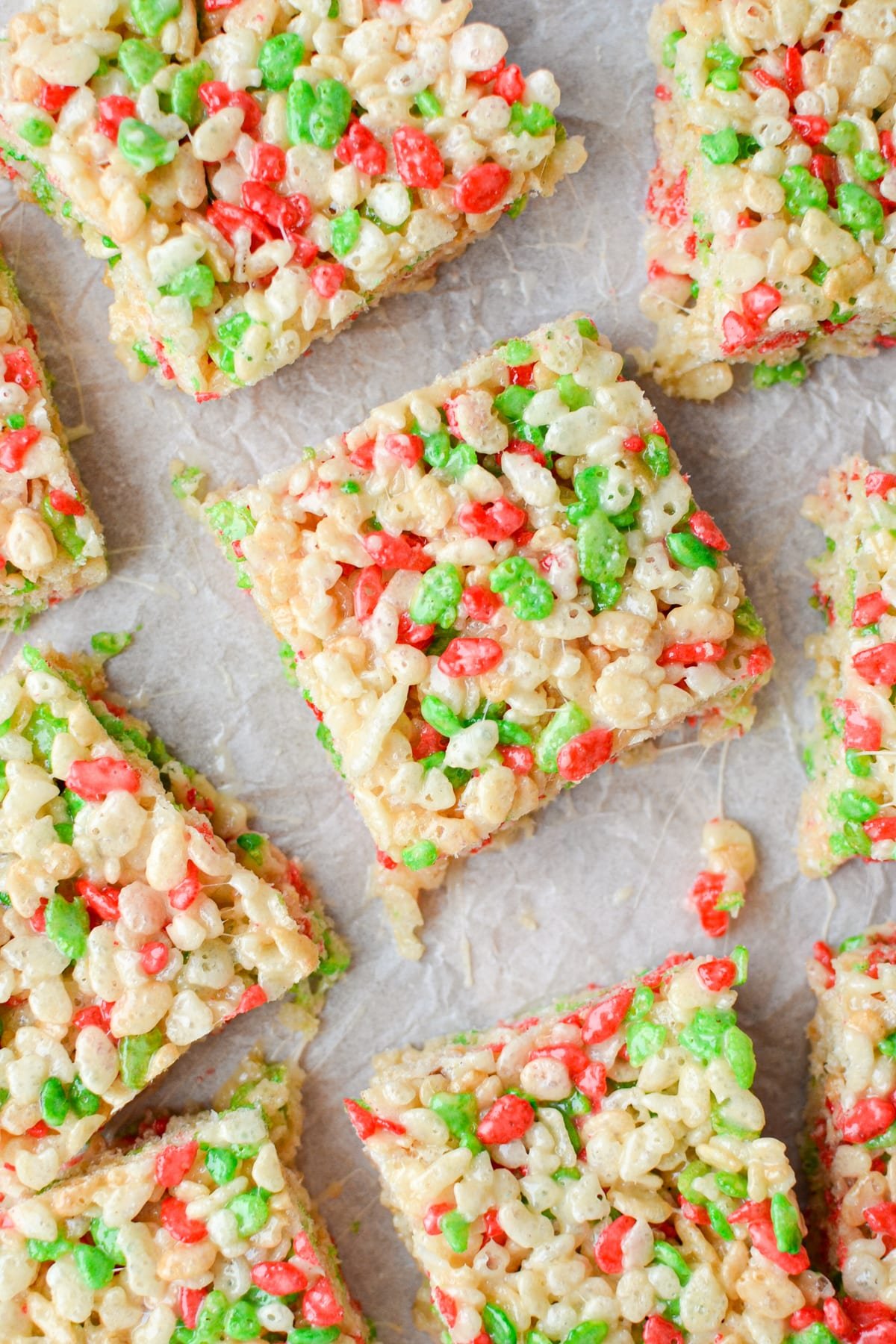 An overhead view of holiday Rice Krispie treats on a parchment lined baking sheet.