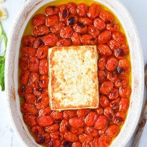 A baking dish with blistered cherry tomatoes and toasty feta cheese.