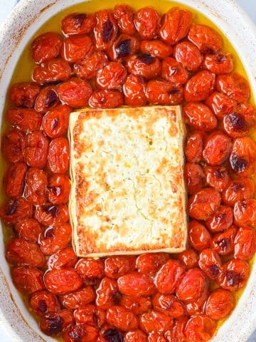A baking dish with blistered cherry tomatoes and toasty feta cheese.