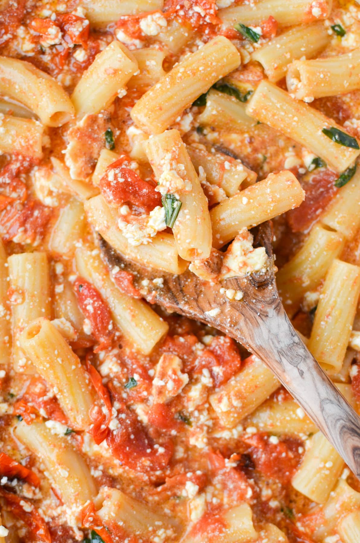 Spooning pasta with a wooden spoon.