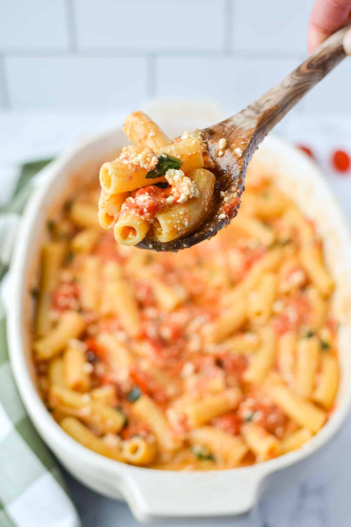 A baking dish of pasta, with a spoon taking a portion.