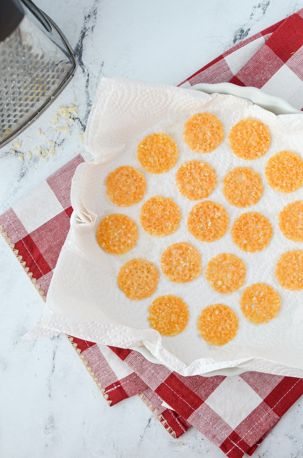 Adding parmesan crisps to a paper towel lined plate.