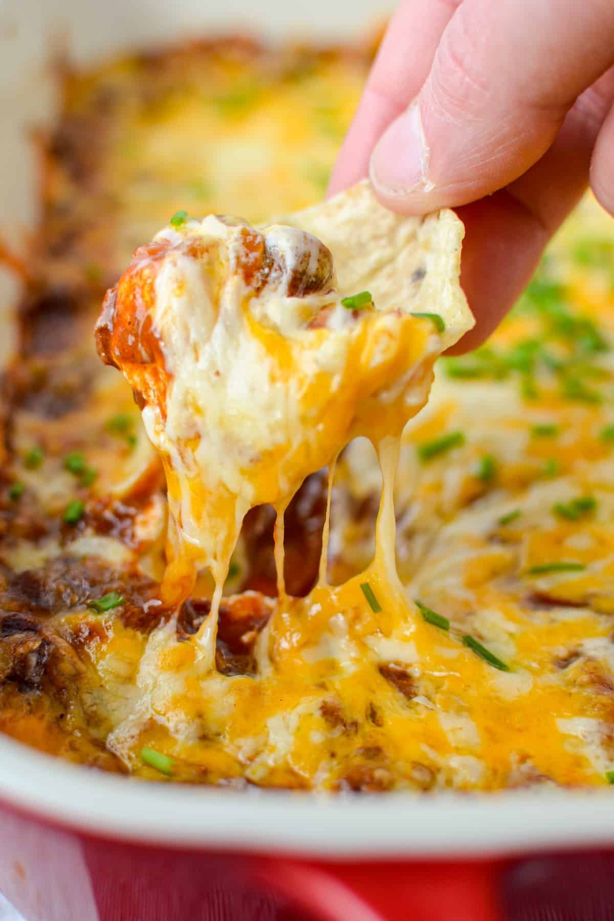 Dipping a scoop tortilla chip into a cheesy dip.