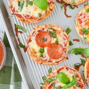English muffin pizzas on a sheet pan.