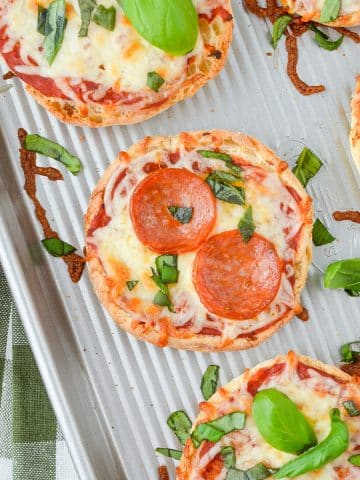 English muffin pizzas on a sheet pan.