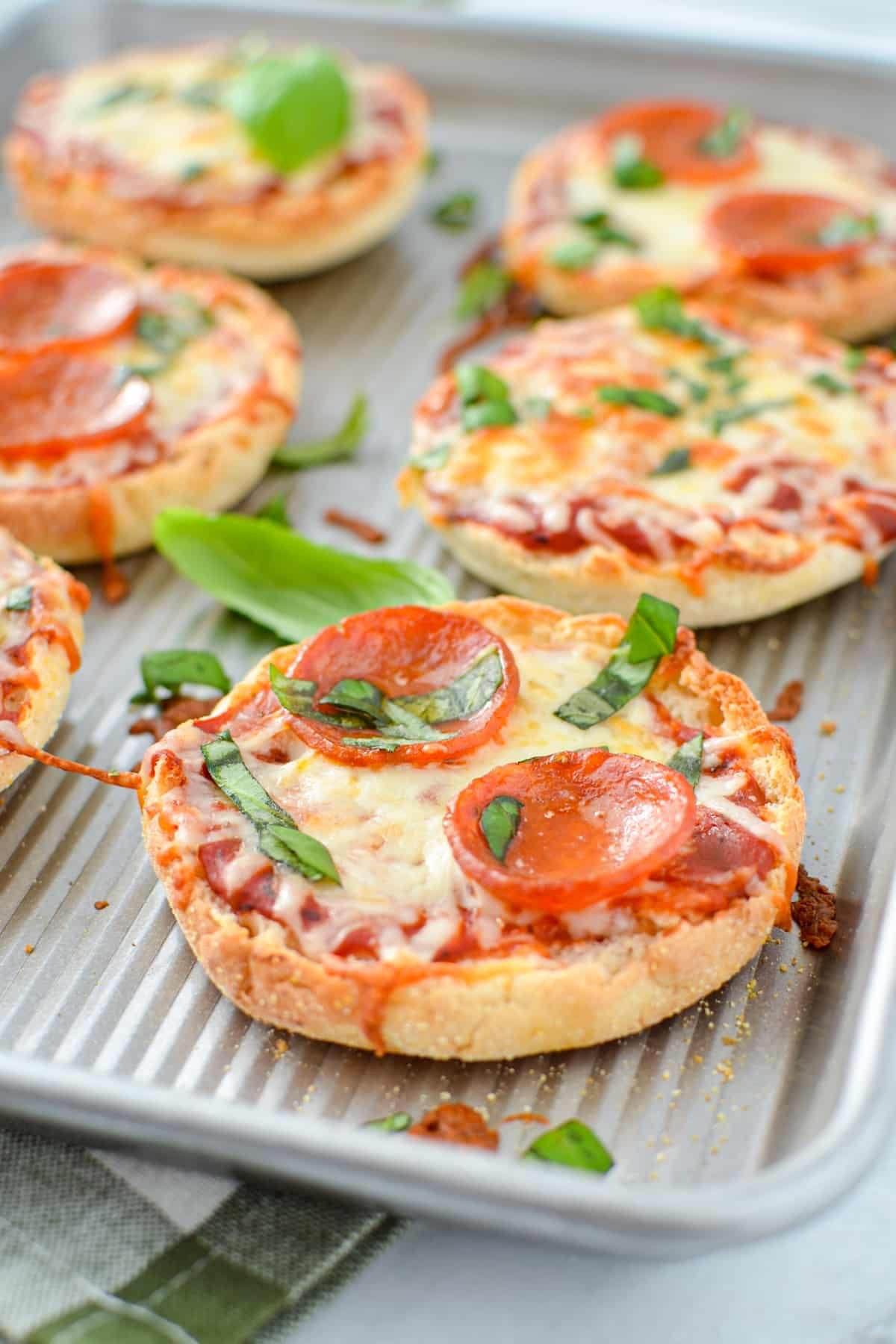 A baking sheet with baked mini pizzas on them.