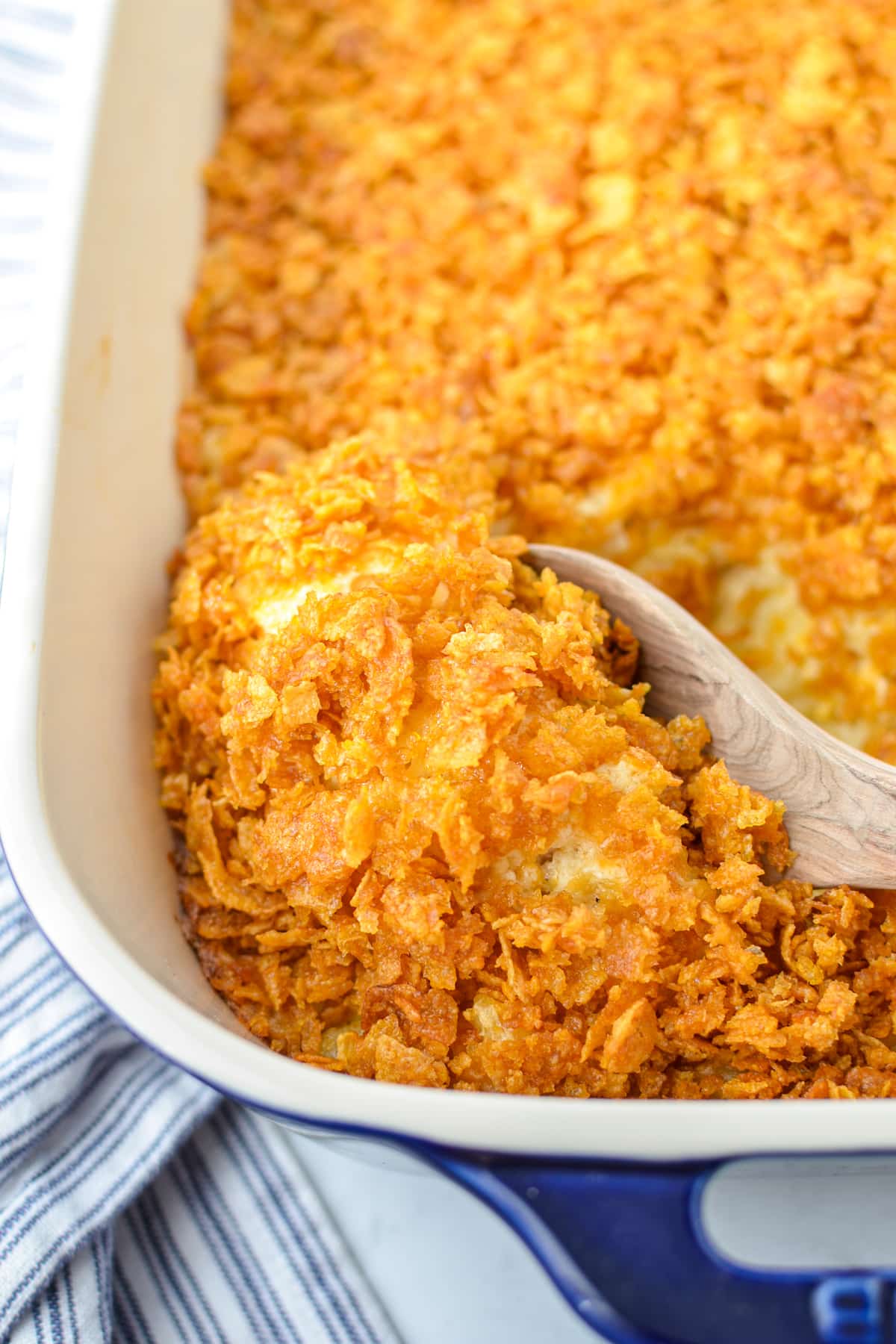 Scooping out hash brown casserole with a wooden spoon.