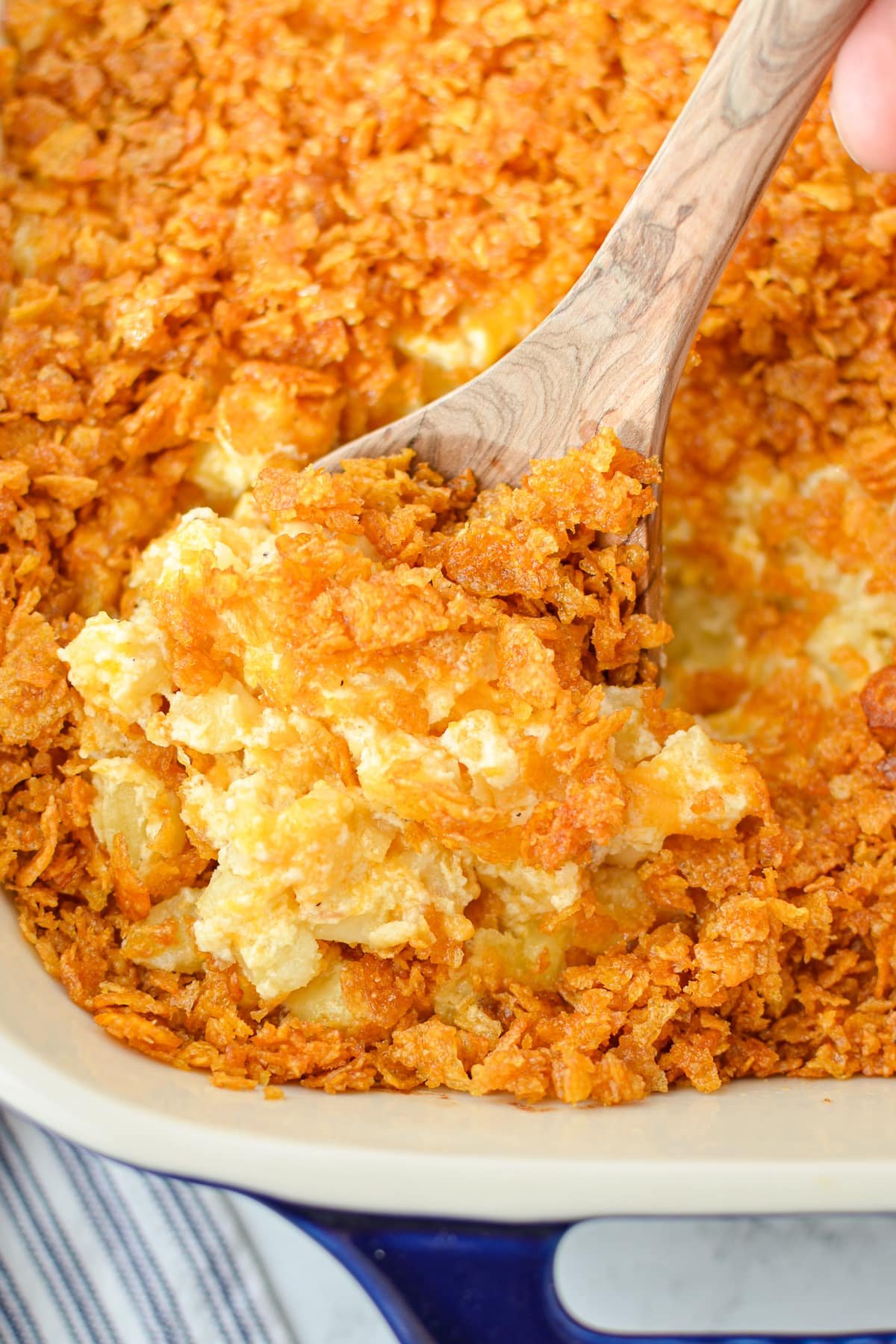 Scooping a portion of hash brown casserole from a baking dish.