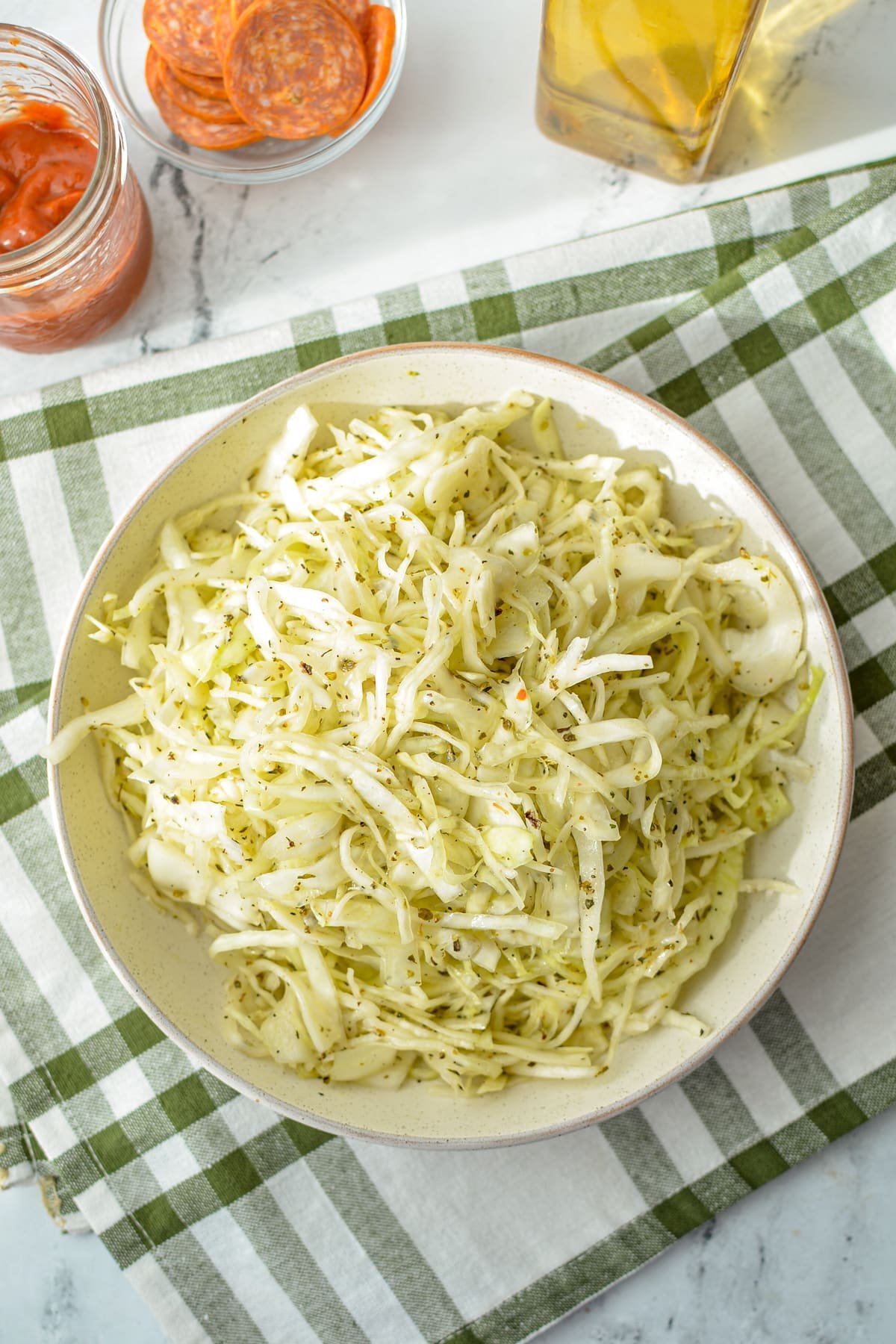 A bowl of shredded cabbage topped with an oil and vinegar dressing.