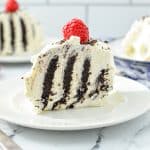 A slice of cake with stripes of dark cocoa cake and whipped cream.
