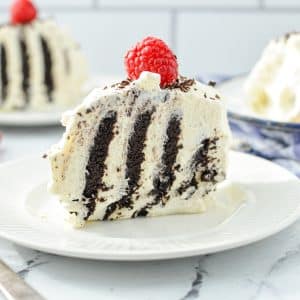 A slice of cake with stripes of dark cocoa cake and whipped cream.