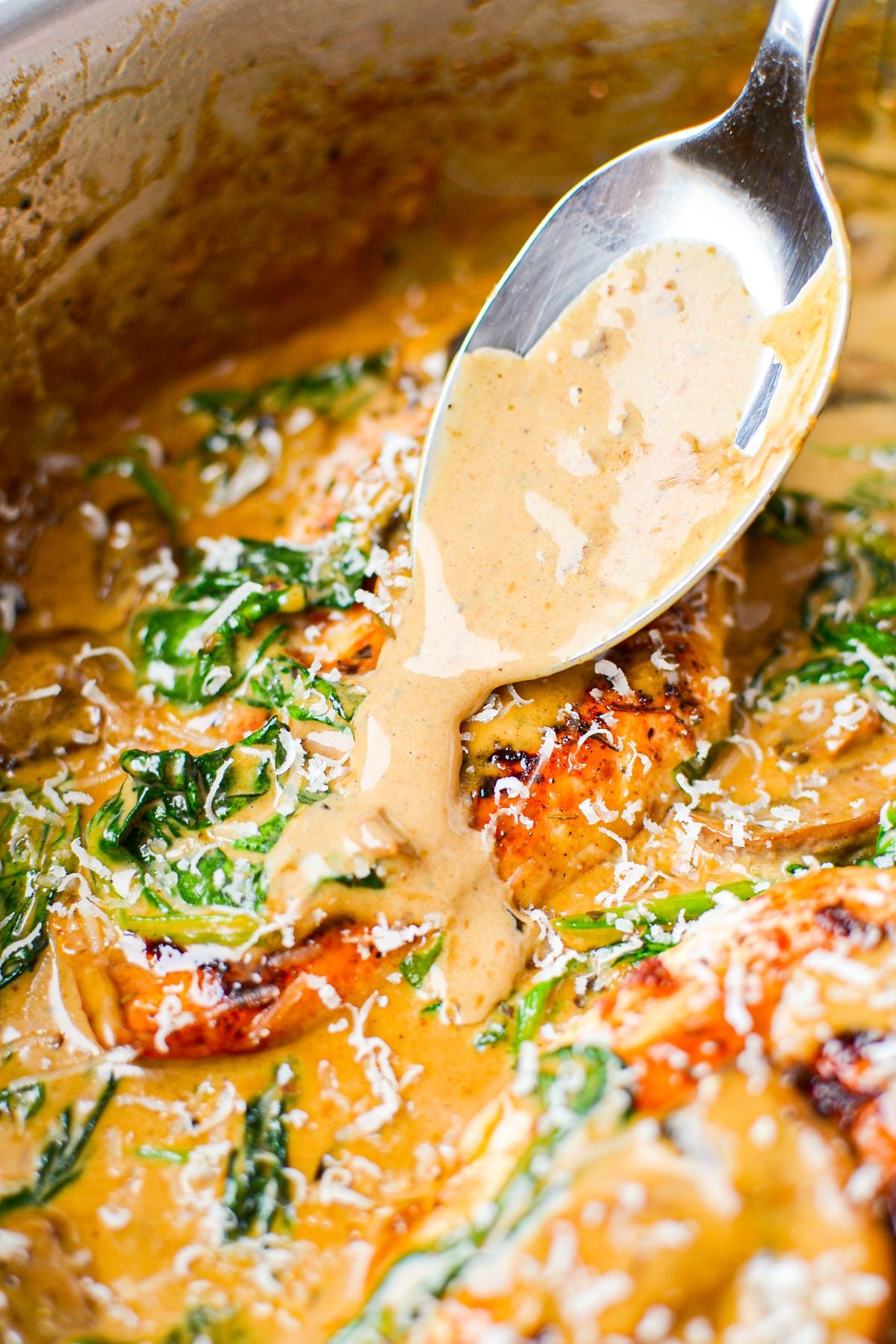 Spooning creamy sauce over a chicken breast.