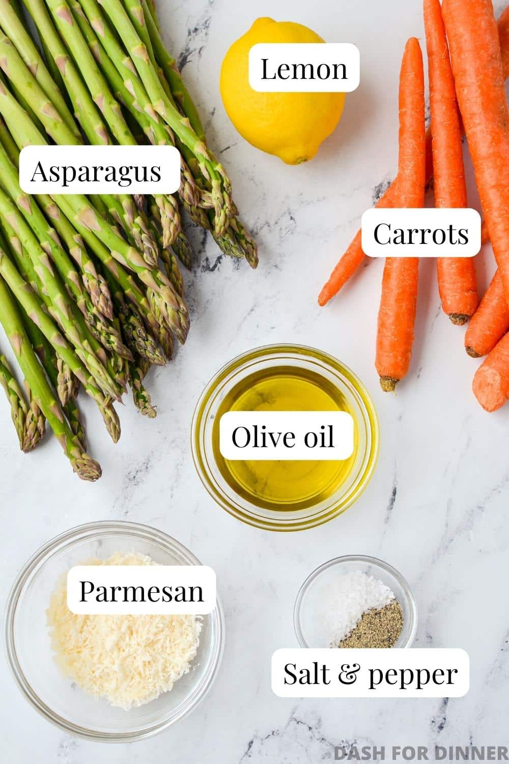 The ingredients needed to make roasted asparagus: carrots, olive oil, seasoning, lemon, Parmesan, and asparagus.