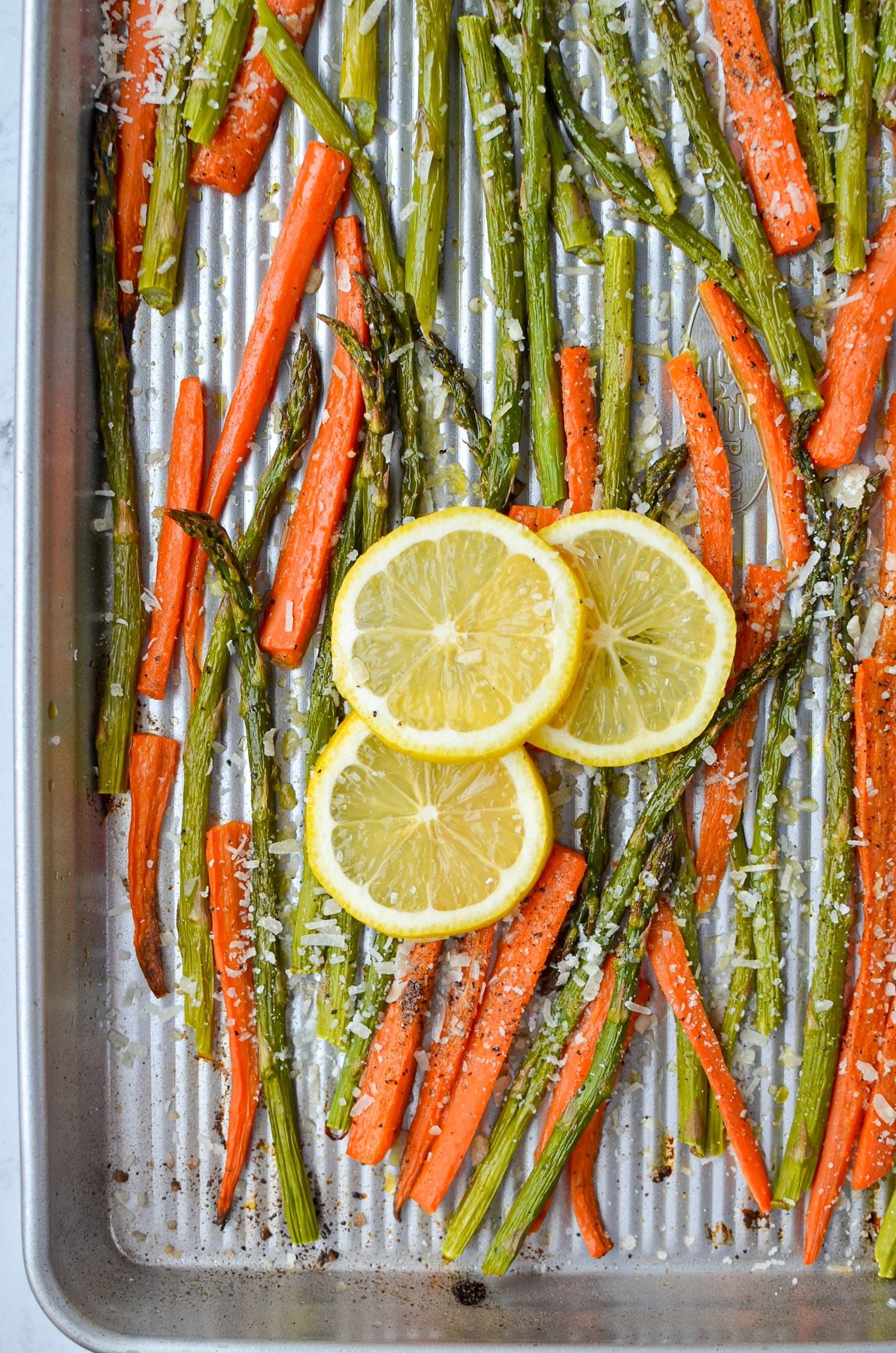 A sheet pan with roasted veggies garnished with lemon.