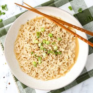 An overhead shot of a bowl of ramen, garnished with green onions and served with chopsticks.