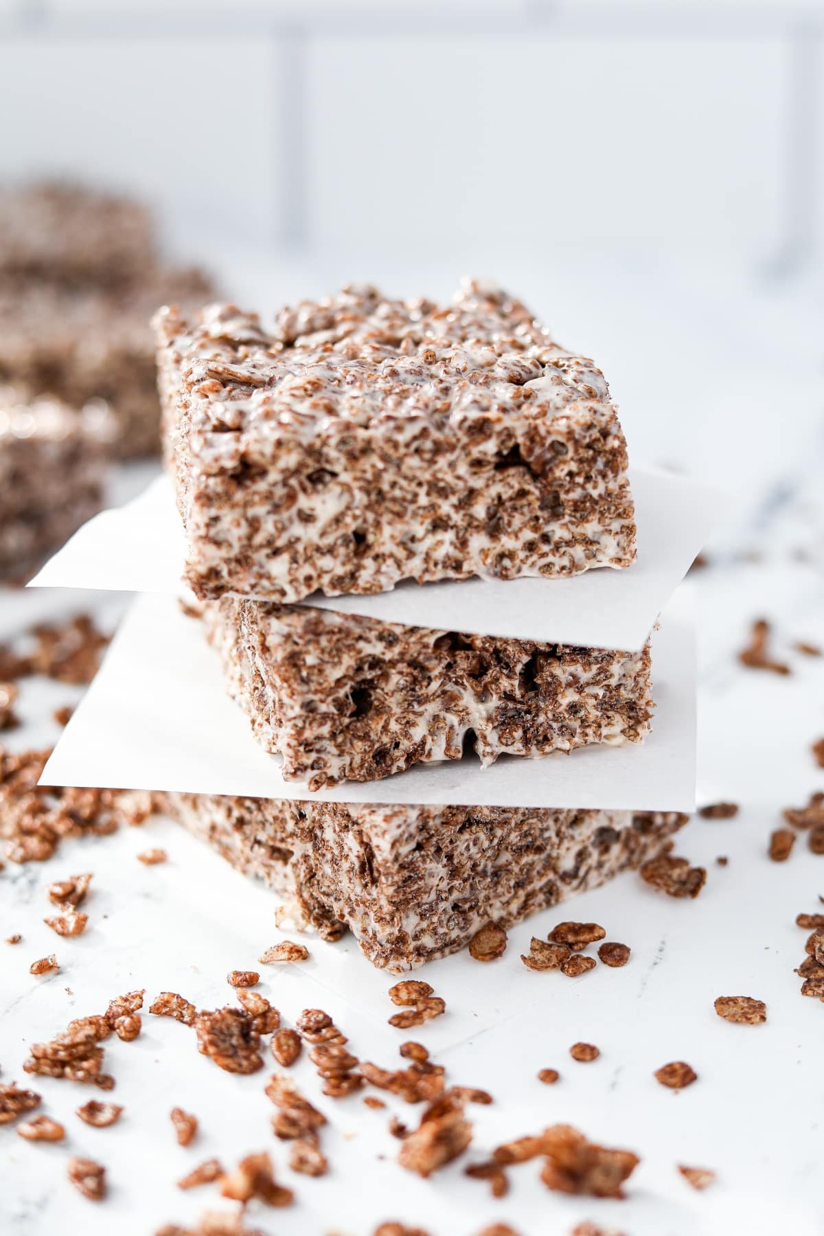 A stack of three chocolate cereal treats on a white surface.