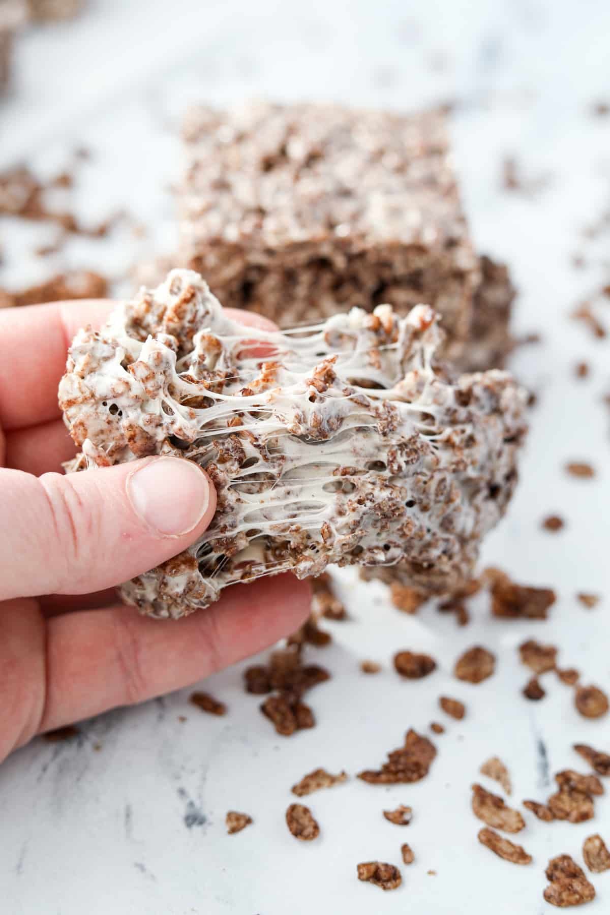 Pulling a cereal treat apart to show the gooey marshmallow.