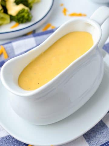 A gravy boat filled with cheese sauce.