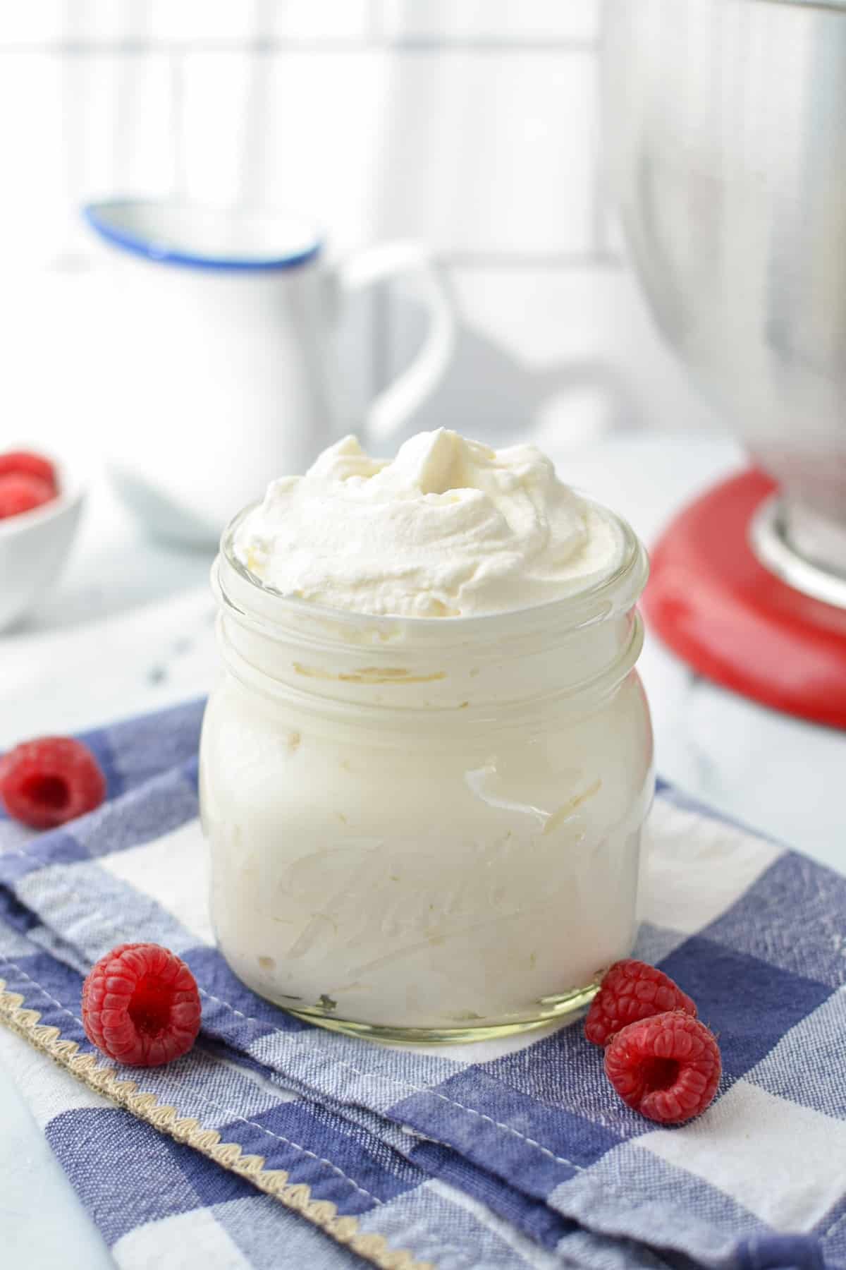 A jar of whipped cream, surrounded by fresh berries.