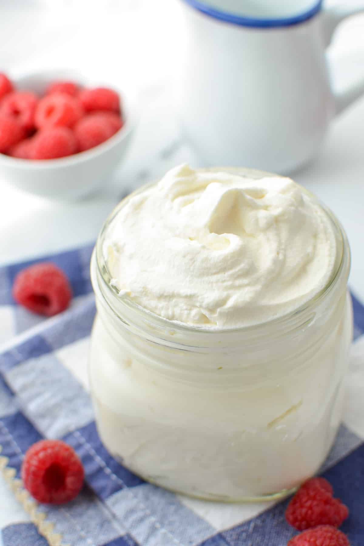 A jar of whipped cream, surrounded by fresh berries.