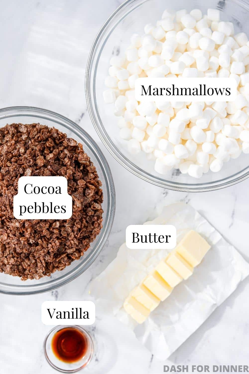 A bowl of marshmallows, Cocoa pebbles cereal, butter, and vanilla.