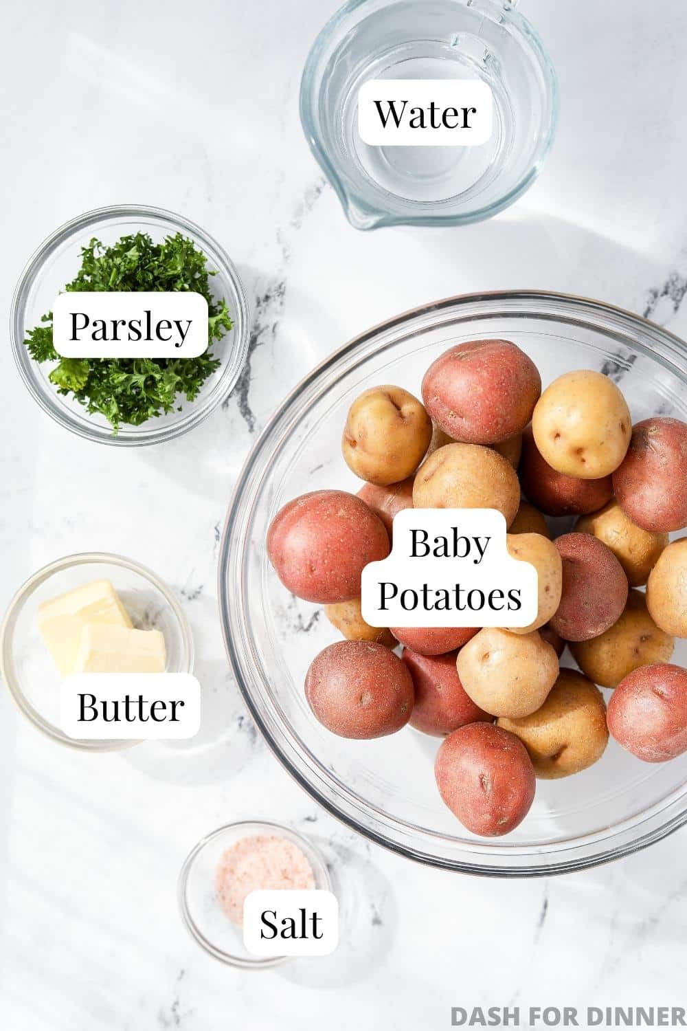 A bowl of baby potatoes, with bowls of butter, salt, parsley, and water.
