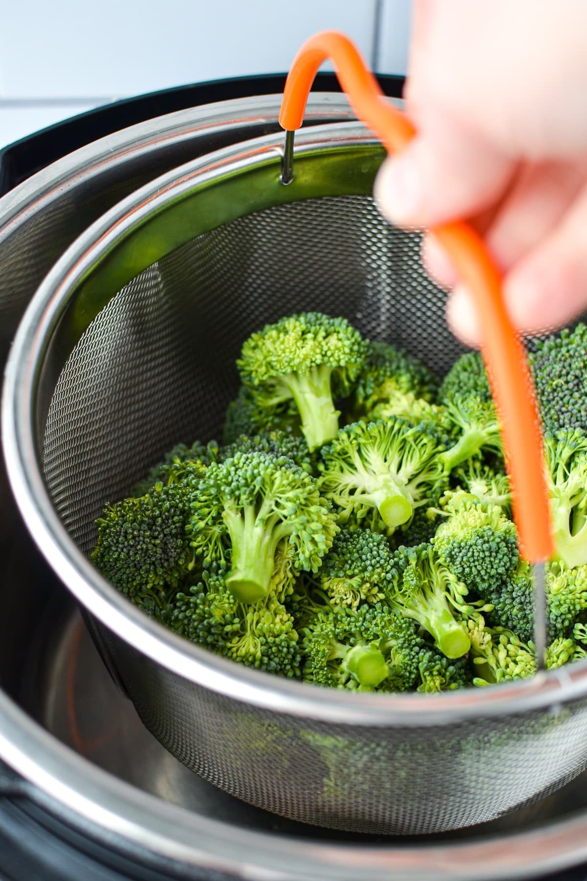 Lowering a steamer basket into an Instant Pot.