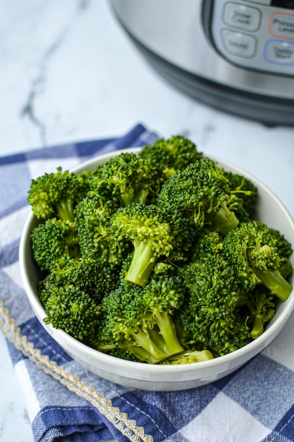 A bowl of broccoli with an Instant Pot in the background.