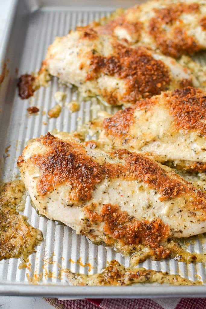 A sheet pan with 4 parmesan crusted chicken breasts on it.