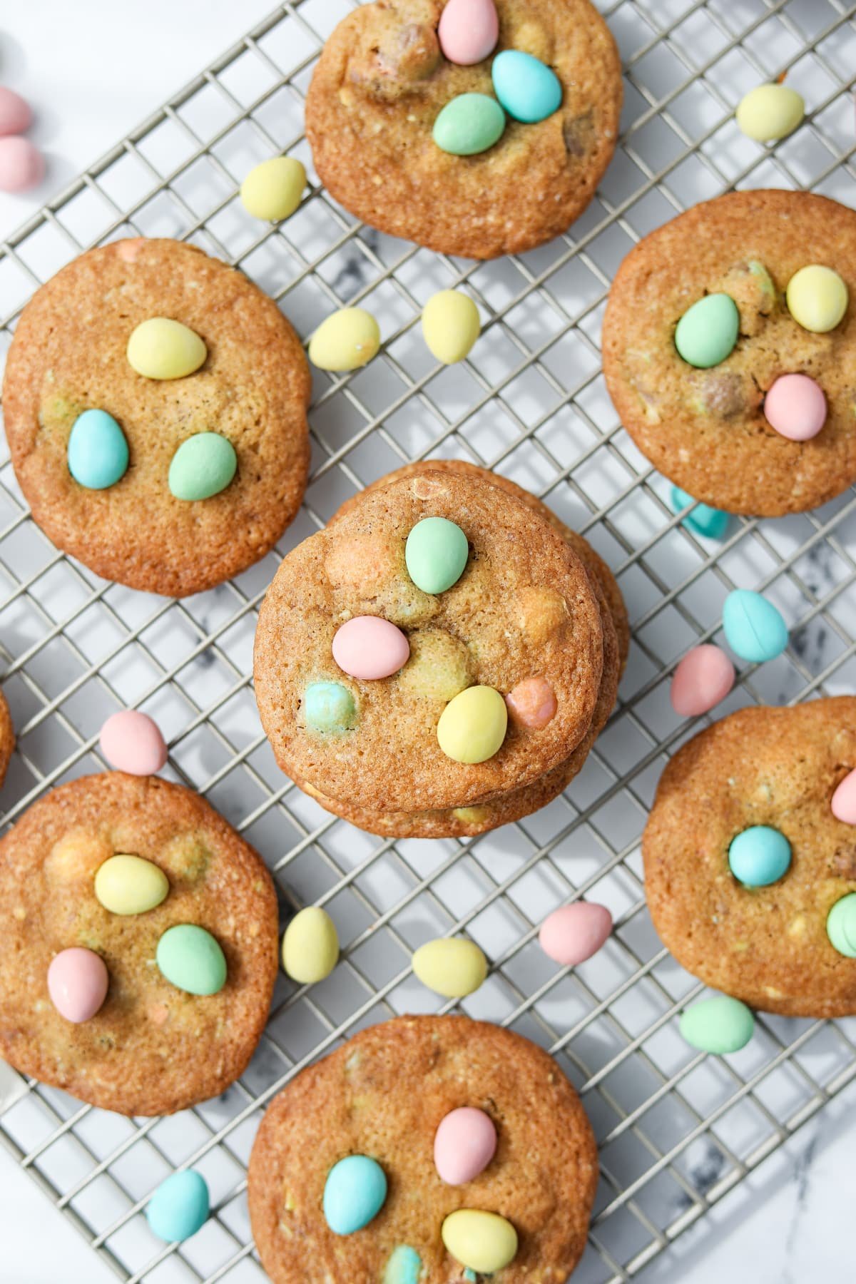 Homemade cookies on a cooling rack, dotted with mini eggs.