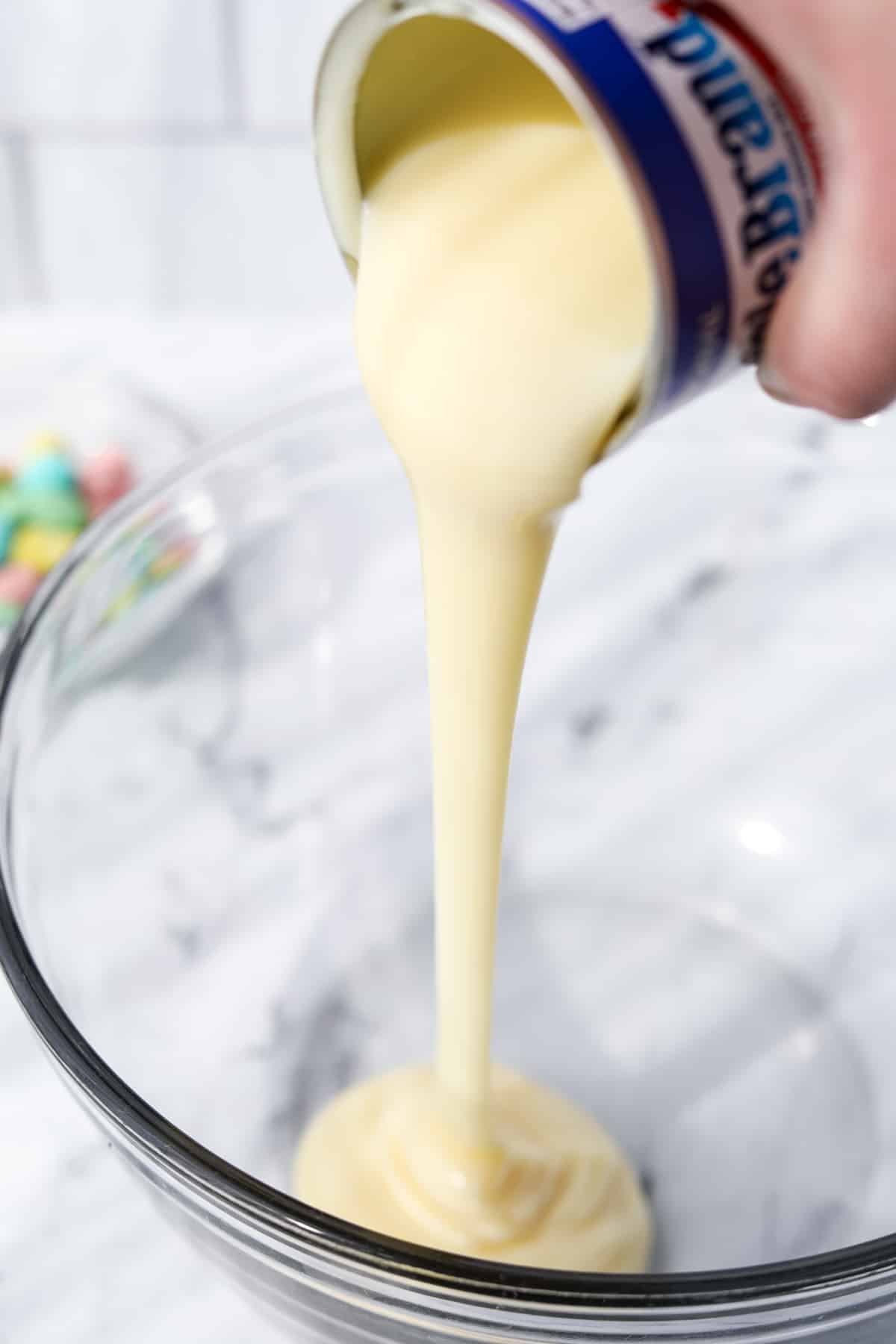 Pouring sweetened condensed milk into a bowl.