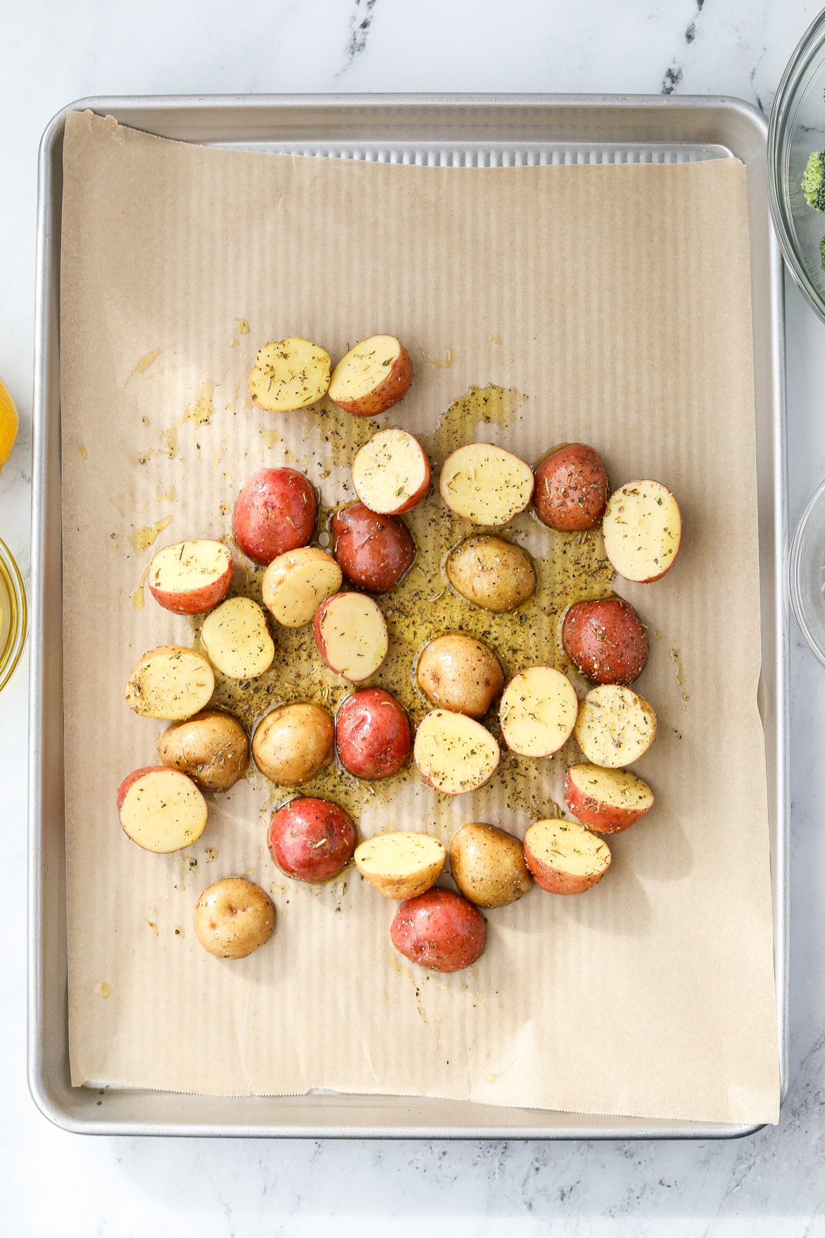Spreading halved and oiled baby potatoes onto a baking sheet.