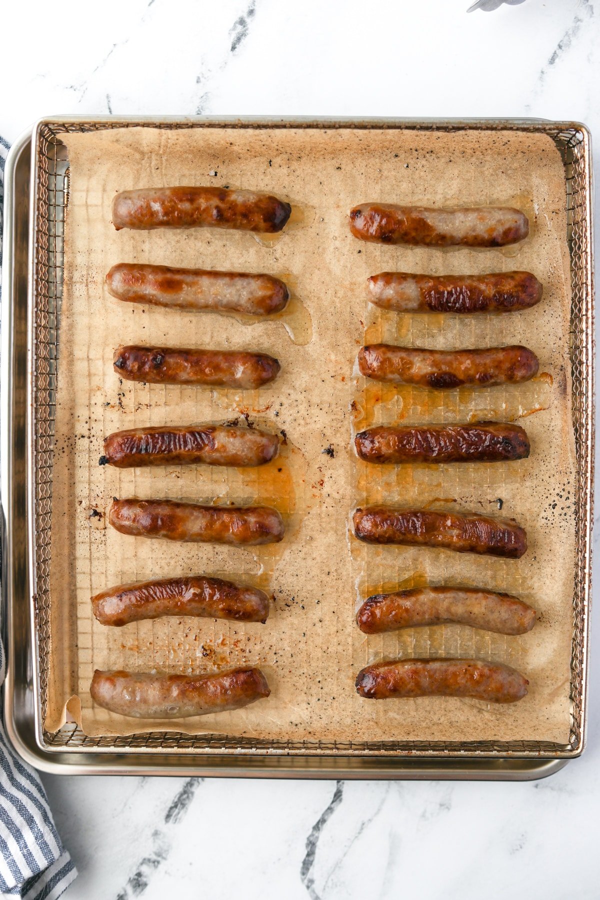 An air fryer tray filled with cooked sausage links.
