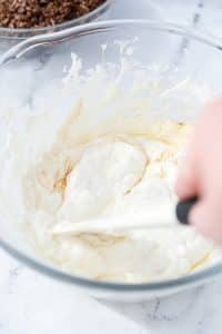 A bowl of melted marshmallows being stirred with vanilla extract added in.