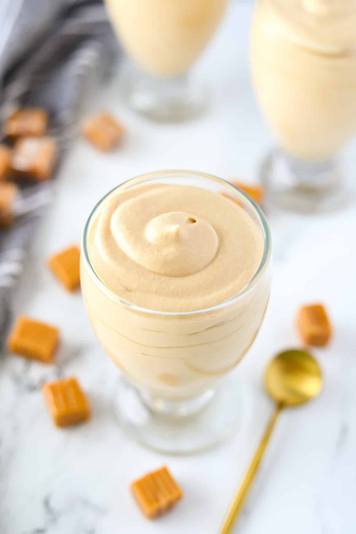 A jar of mousse with a gold spoon on the side.