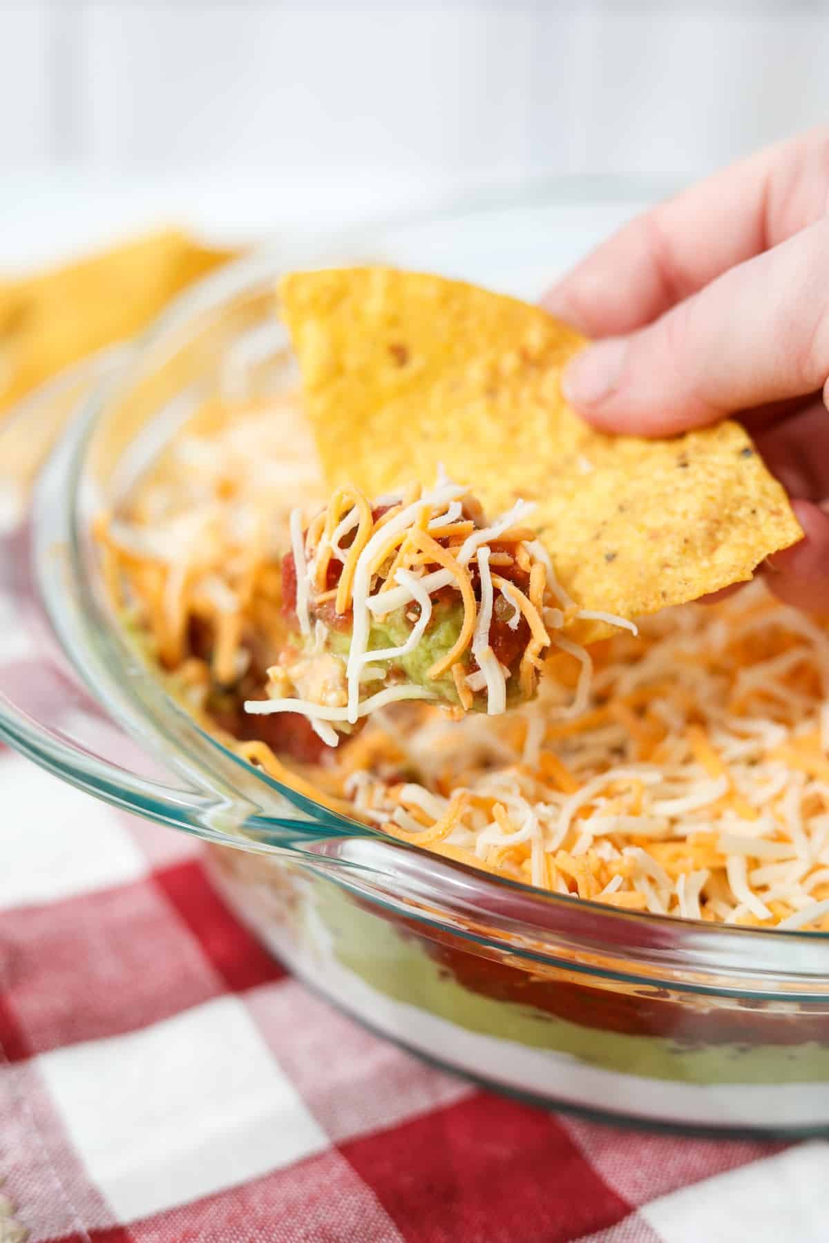 A tortilla chip dipped into a cold layer dip.