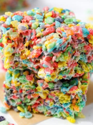 Two cereal treats stacked , made with Fruity Pebbles.