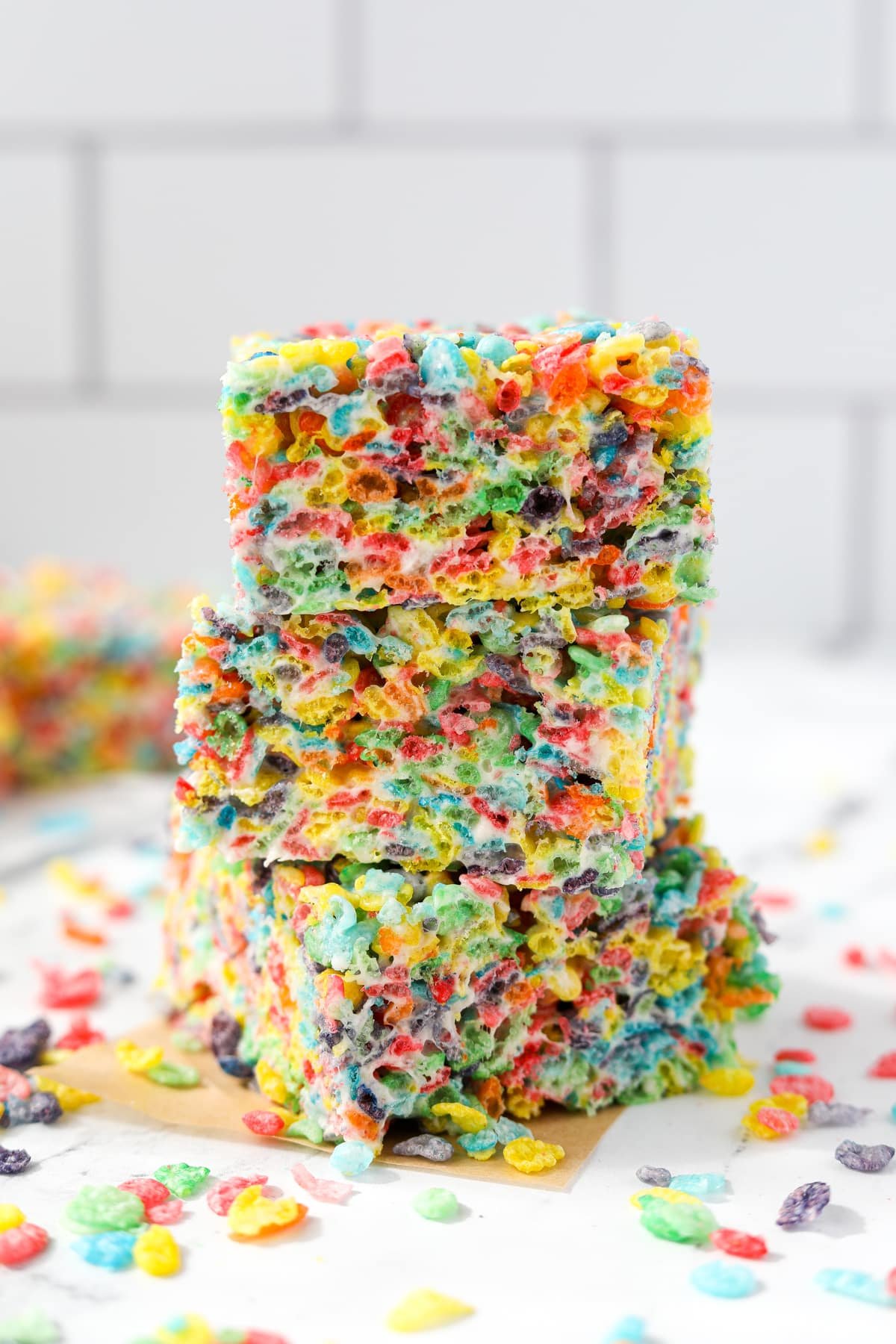 A stack of three cereal treats with a white tile background.