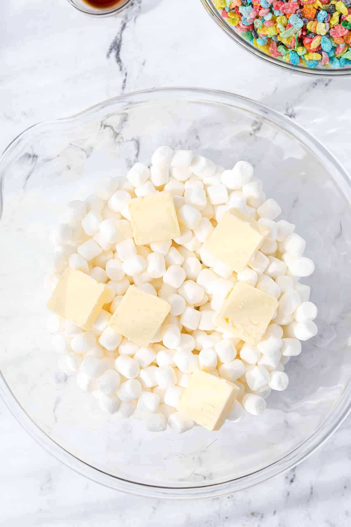A bowl with mini marshmallows and cubes of butter.