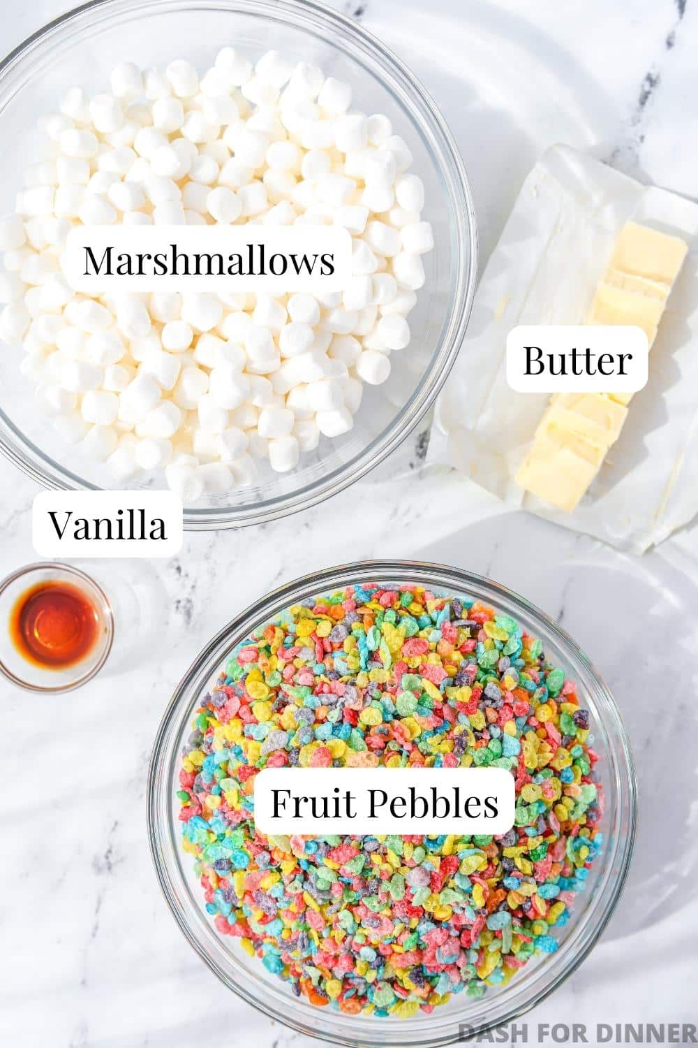 A bowl of mini marshmallows, fruity pebbles cereal, a stick of butter, and some vanilla extract.