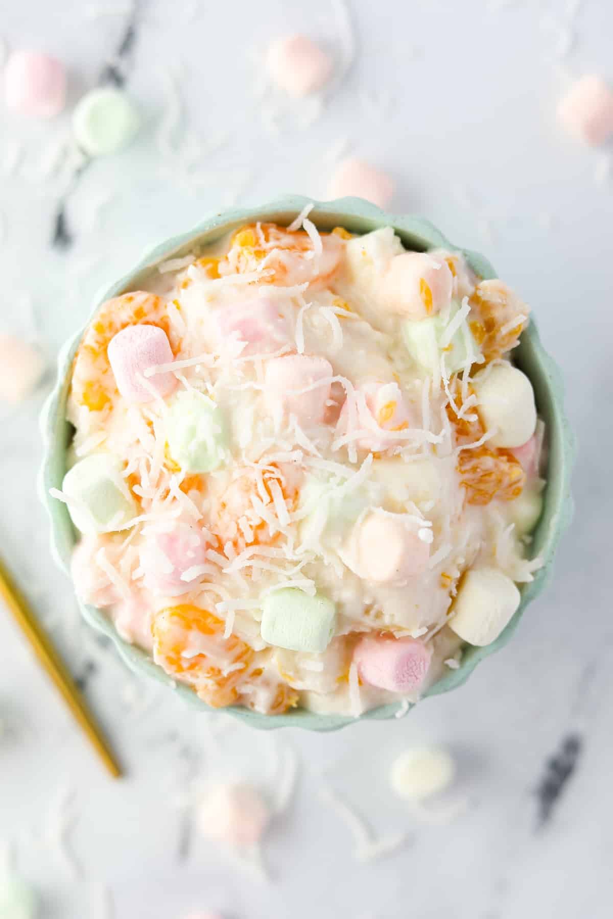 A bowl of marshmallow fruit salad garnished with coconut.
