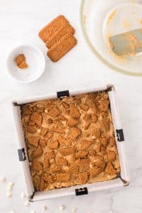 Topping a pan of blondies with biscoff cookies.