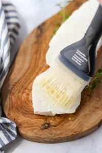 Brushing oil on a slice of halloumi cheese.