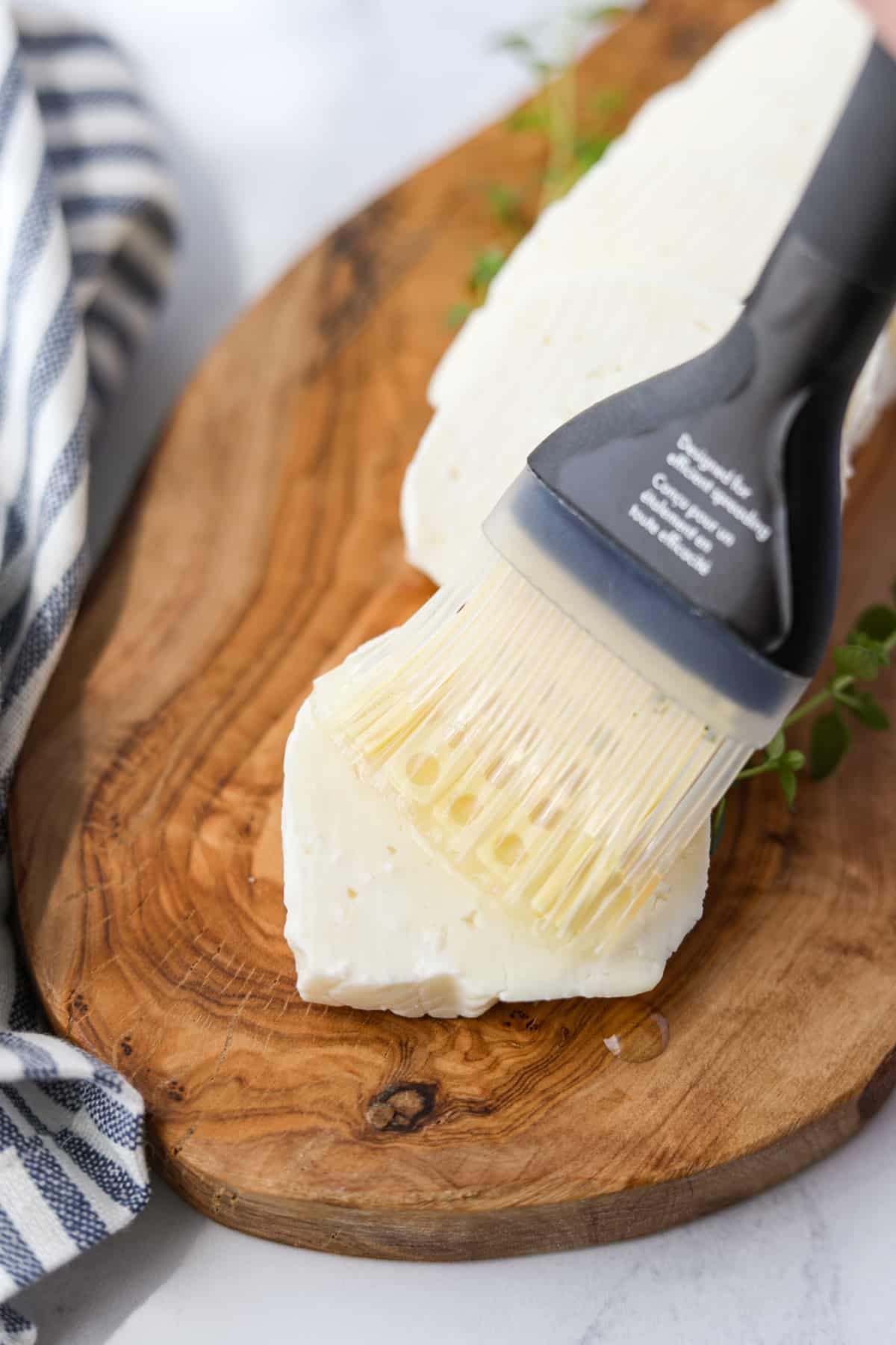 Brushing oil on a slice of halloumi cheese.