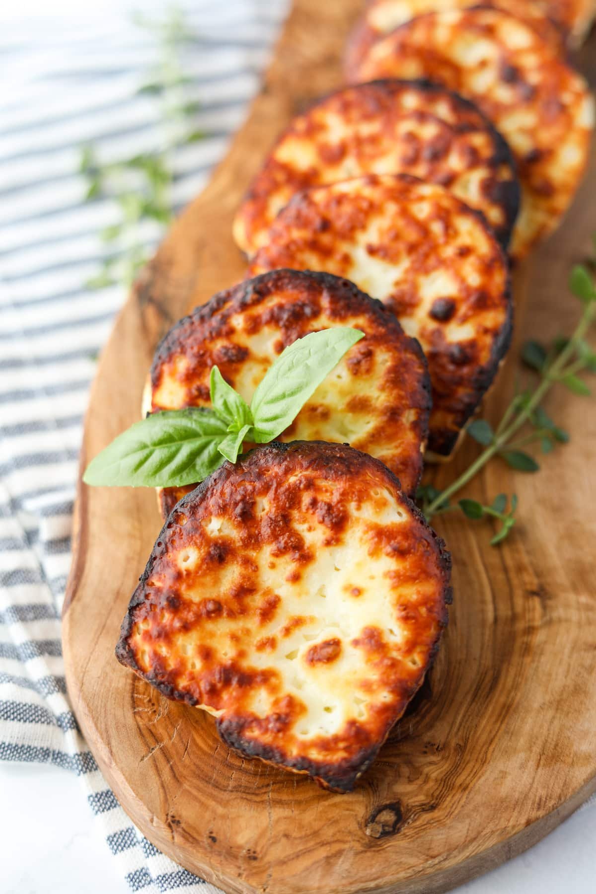 Fried cheese on a wooden board, garnished with basil.