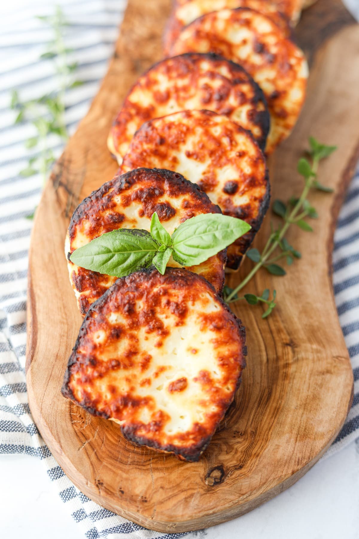 Garnishing a slice of fried halloumi cheese with fresh basil.